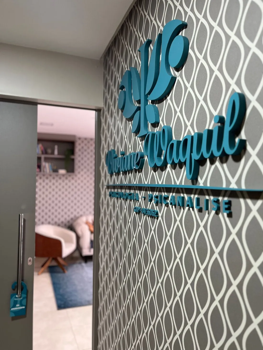 Entrada do consultório com o logotipo de Viviane Waquil, psicologia e psicanálise, na parede